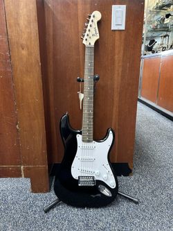 Fender Squier Stratocaster electric guitar in classic black finish, complete with a padded soft gig bag case.