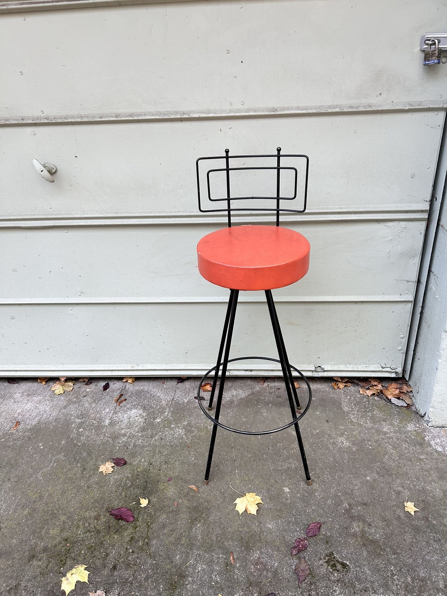 mid-century modern Frederic Weinberg-style bar stool featuring a black iron frame and a round cushioned Swivel seat