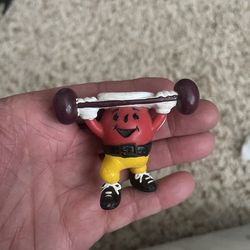 vintage 1990s Kool-Aid Man weightlifting PVC figure produced by Kraft Foods.        It is a small, 2-inch tall toy figure of the red Kool-Aid mascot l