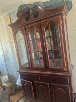 traditional dark wood china cabinet with a decorative arch top and glass-paneled doors.