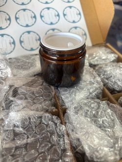 Selling a set of 12 small black containers/jars, individually wrapped and packed in the original box. They appear to be new and unused.