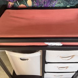 Brown changing table with three drawers, laundry basket, changing pad and cover 