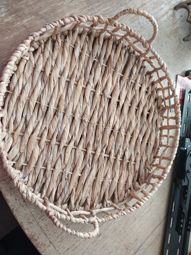 Beige Steel Frame Round Woven Food Tray Or Wall Decor features strands of grass woven into a spiral pattern on the front and On Steel rim.