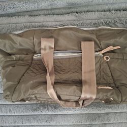 The Skip Hop Diaper Bag is a large, unisex baby diaper bag made of durable polyester material in a sleek olive solid color.