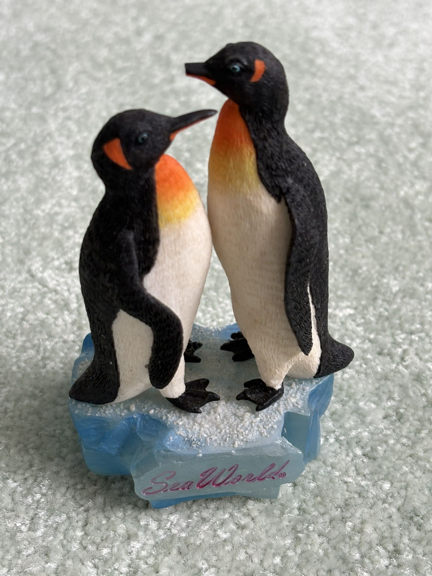 A pair of penguin figurines on a base from SeaWorld