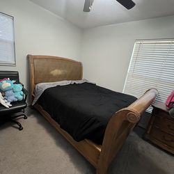 Solid wood sleigh-style queen bed frame. Includes headboard, footboard, and side rails.
