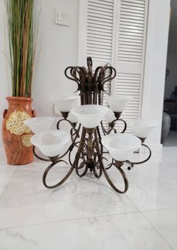 Chandelier featuring curved metal details, a bronze finish, and nine white frosted glass shades.