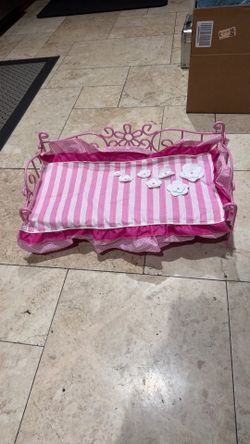 Our generation scroll daybed for 18-inch dolls featuring a pink metal scrollwork frame and a pink-and-white striped mattress set