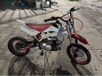 • Se trata de una motocicleta pit bike JS Moto de 125cc con una carrocería de color rojo y blanco.