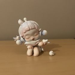 The product is the "Chirping" figure from the POP MART SKULLPANDA The Warmth Series.