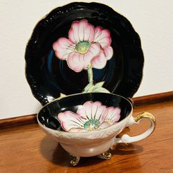 Vintage glossy white and black 3 footed china tea cup and saucer set with pink flower and gold accents