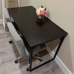 Modern black desk with 2 gray office chairs.