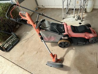 corded electric Black+Decker lawn mower with a grass collection bag, paired with an orange Black+Decker string trimmer