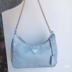 Baby blue nylon half-moon crossbody bag, silver chain strap with triangular logo shoulder strap, back-to-back crossbody style underarm bag