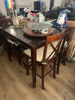 Bar top table with four wooden chairs and cushions
