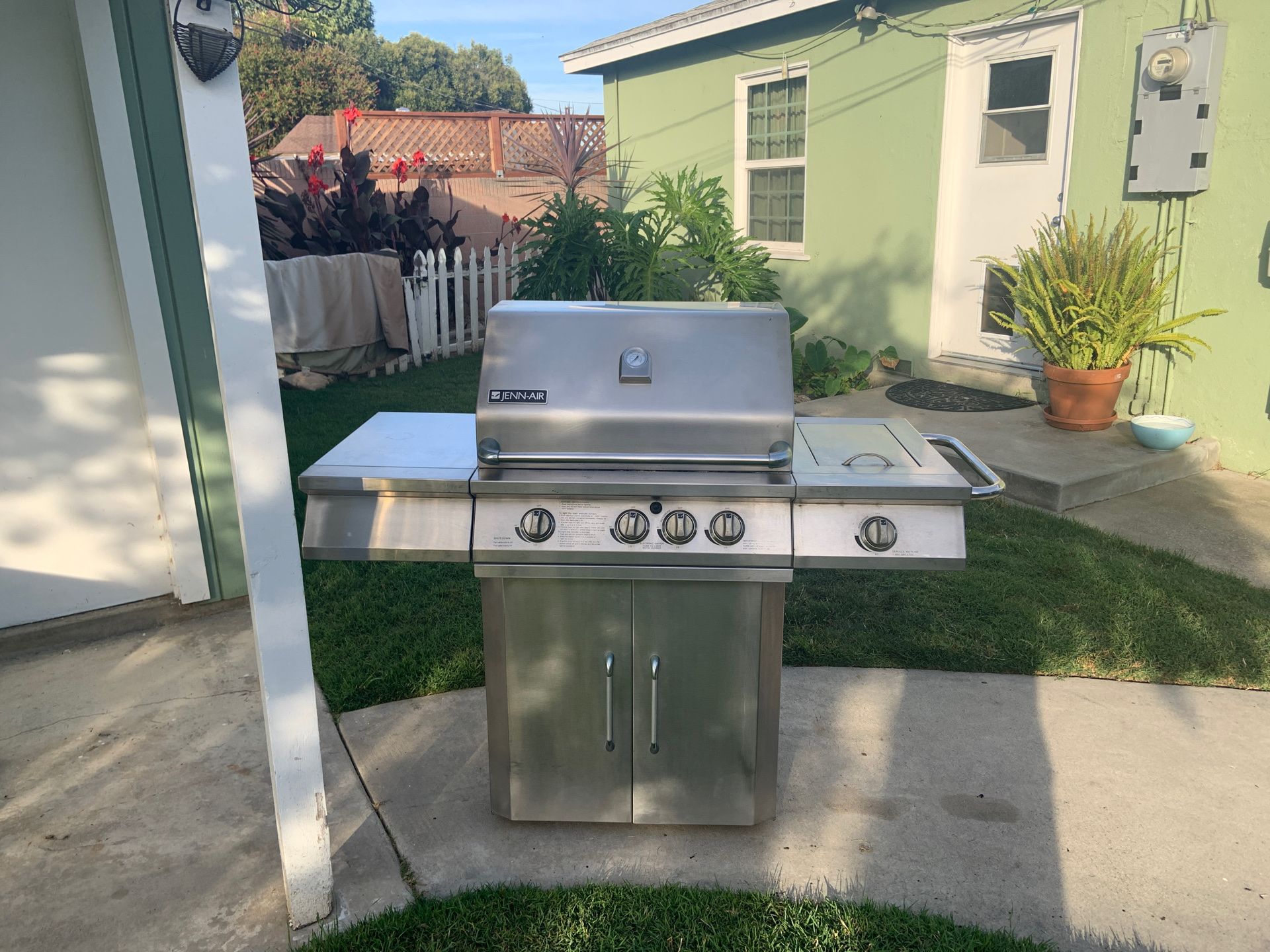 Stainless steal JennAir BBQ with stainless grills and a canvas cover