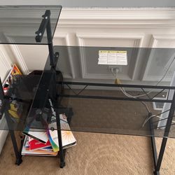 Black frame glass computer desk with shelves.