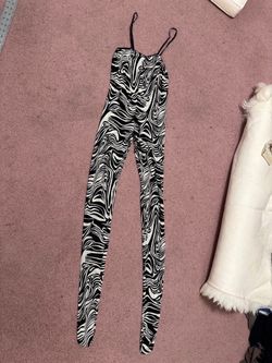Eye-catching black and white swirl print jumpsuit with thin spaghetti straps. Sleek, fitted silhouette that flatters the figure. Lightweight, stretch 
