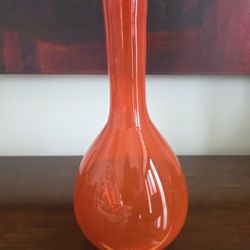 Mid-century modern blown art glass vase in orange, with bulbous base and narrow neck. 