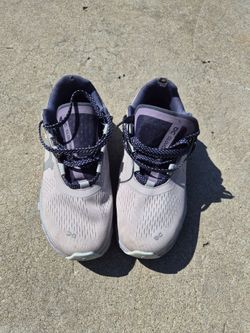 On Cloudmonster running shoes, likely in the Cinder/Fog colorway.