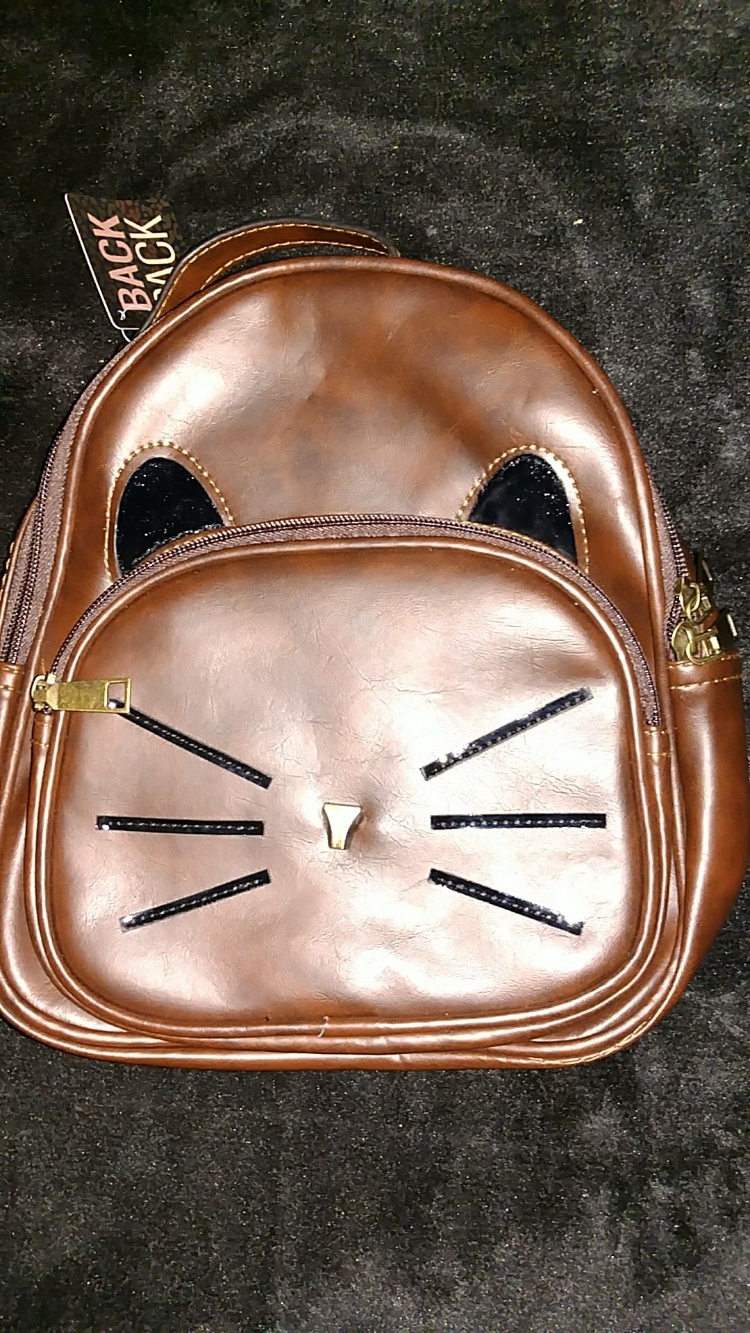 A brown kids backpack with a cat