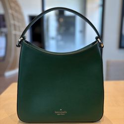 Beautiful Kate Spade New York handbag. Has a gorgeous dark green color and textured material. Single top handle. Inside has a black lining with spade 
