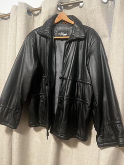 Genuine black leather jacket from Wilsons Maxima. This garment has a full-zip front closure and a high collar. It features adjustable drawstring toggl
