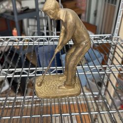 a vintage brass figurine of a golfer preparing to swing