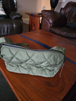 Vera Bradley Lightweight quilted belt bag in olive green. Top zipper closure. Adjustable strap for hands-free wear. Casual, versatile design.