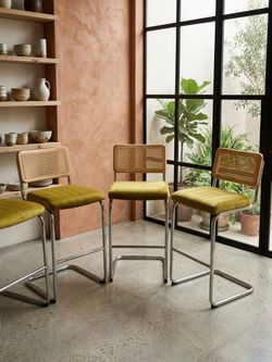 Set of 4 olive green velvet bar stools with stylish rattan backs and chrome frames.