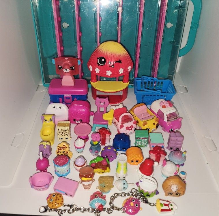 lot of Shopkins figures, diecast cars, display case, and charm bracelot