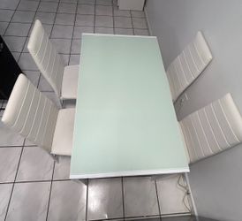 4 sillas y una mesa con cristal