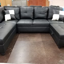 Black faux leather sectional with a matching storage ottoman