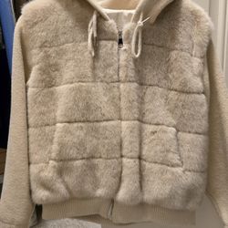 cream-colored hooded jacket with a soft faux-fur padded front and knit sleeves.