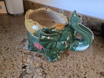 This is a vintage green ceramic elephant planter with a lucky trunk up design. 