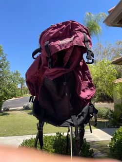 maroon and black Coleman brand hiking backpack featuring a large main compartment with a drawstring closure and a top lid