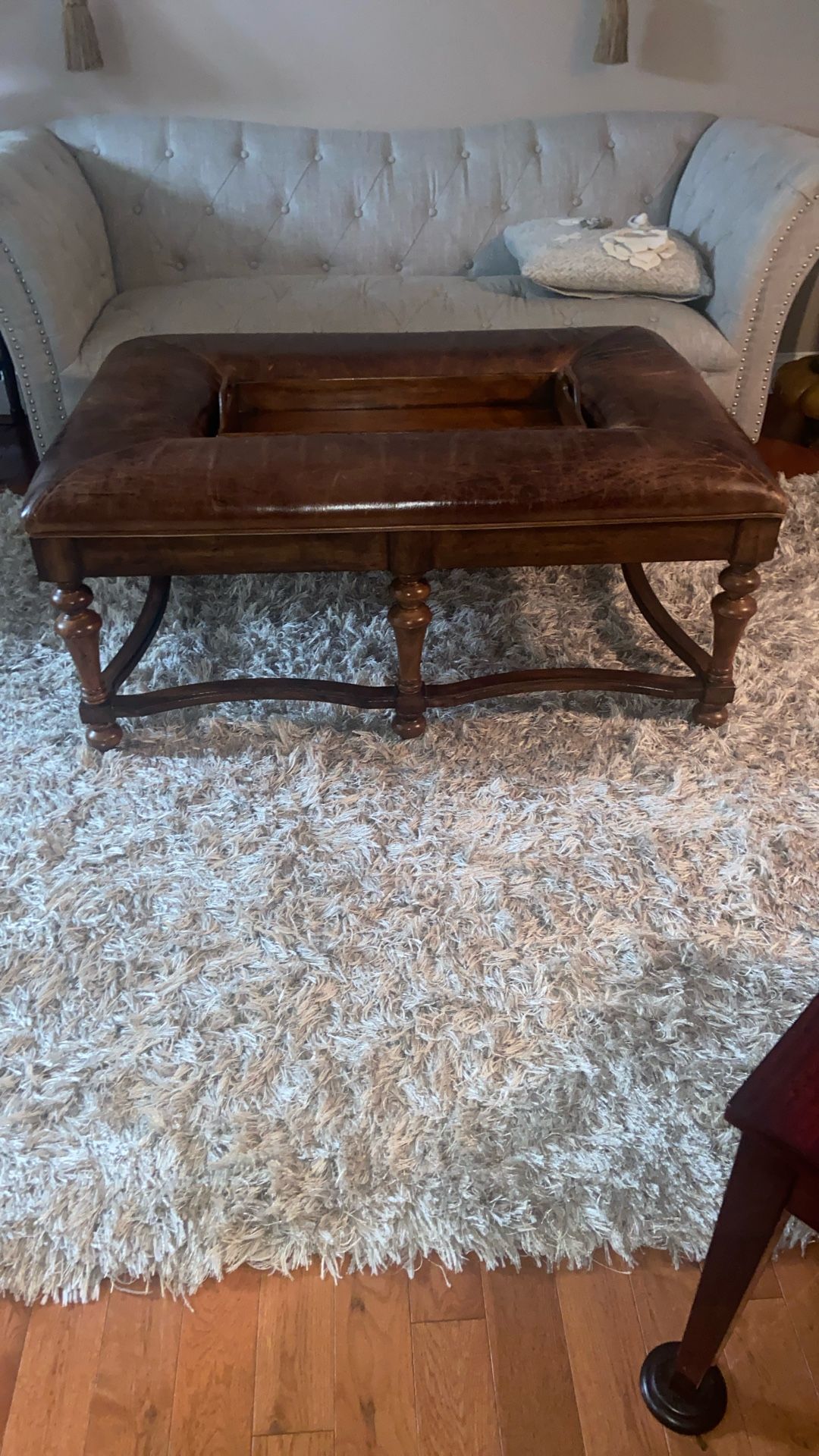  Brown leather ottoman with a wooden frame and an integrated tray. 