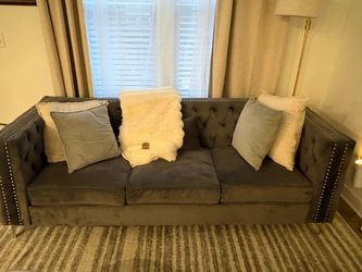 This is a dark gray velvet Chesterfield-style sofa featuring elegant button tufting and metallic nailhead trim along the squared arms.