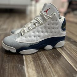 Air Jordan 13s in the “Flint” colorway (white, navy blue, and gray).