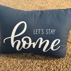 Navy blue throw pillow with white lettering that says let’s stay home