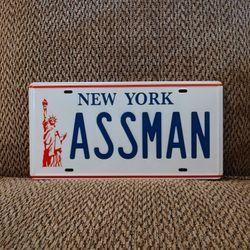 SEINFELD ASSMAN METAL LICENSE PLATE.  12" X 6".  NEW.  PICKUP ONLY.
