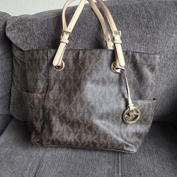 Spacious Michael Kors tote bag has signature brown monogram coated canvas with tan leather straps. Gold-tone MK charm and hardware are attached. Inter