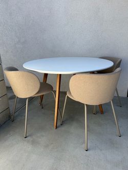 Round white dining table with 4 beige chairs