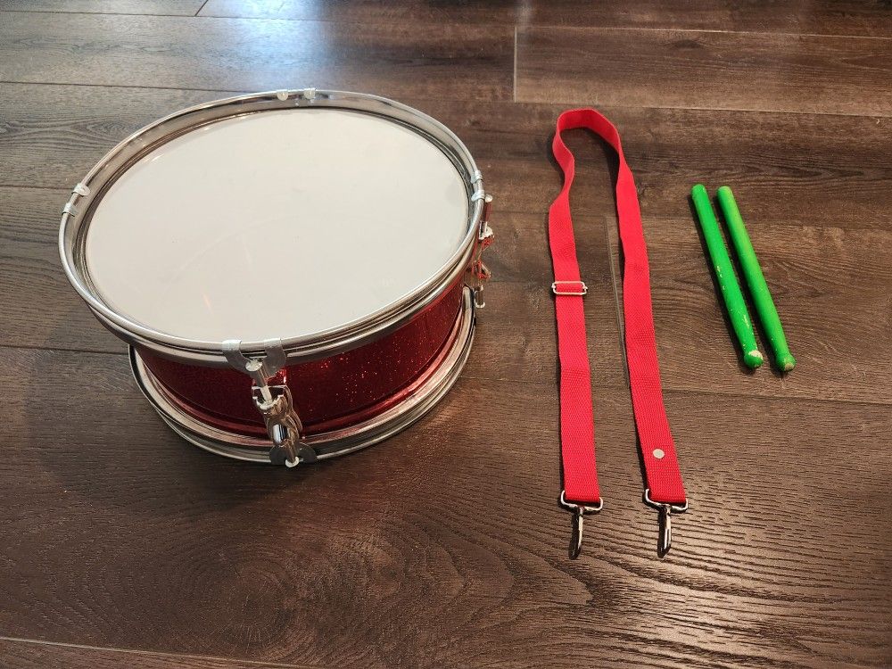 12" D 5.5" H Red Snare Drum set, complete with a strap and drumsticks. 