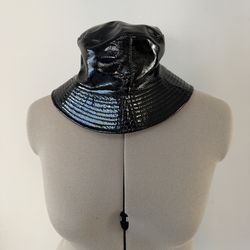 Reversible statement hat. One side features sleek black patent finish, the other side has bold red Chinese-style dragons. Unique, eye-catching design.