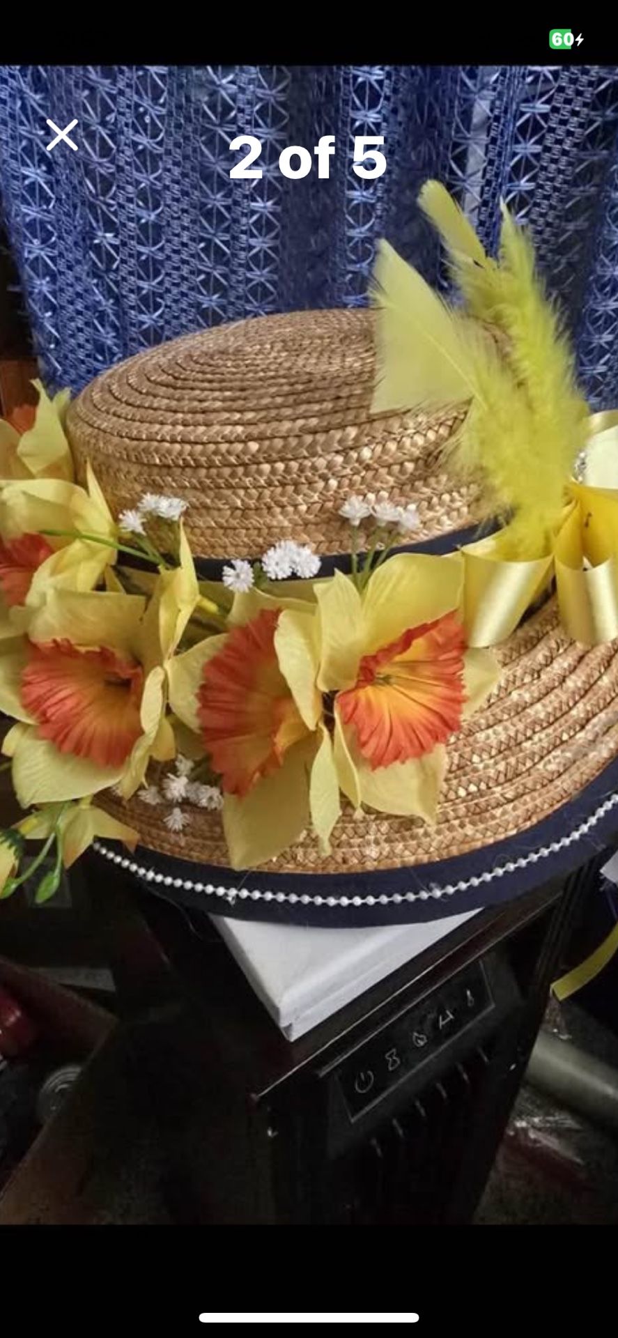 Boater hat with a dark ribbon, a pearl-like trim, and a bouquet of yellow & peach flowers & feathers