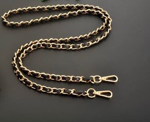 Gold metal crossbody bag strap with leather strap.