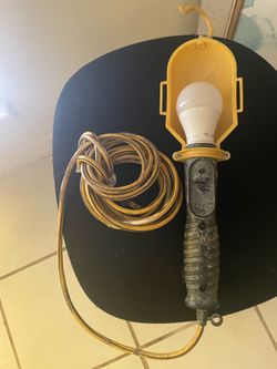 portable incandescent work light with a yellow metal guard and a hanging hook