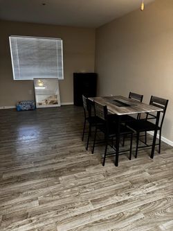 * Item: Dining table and 4 chairs * Table shape: Rectangular * Tabletop color: Grayish-brown wood grain * Chair color: Black with wood-look backrests 