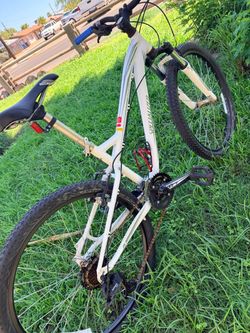 This is a white Specialized Myka women's mountain bike featuring a patterned frame design and a blue handlebar grip.